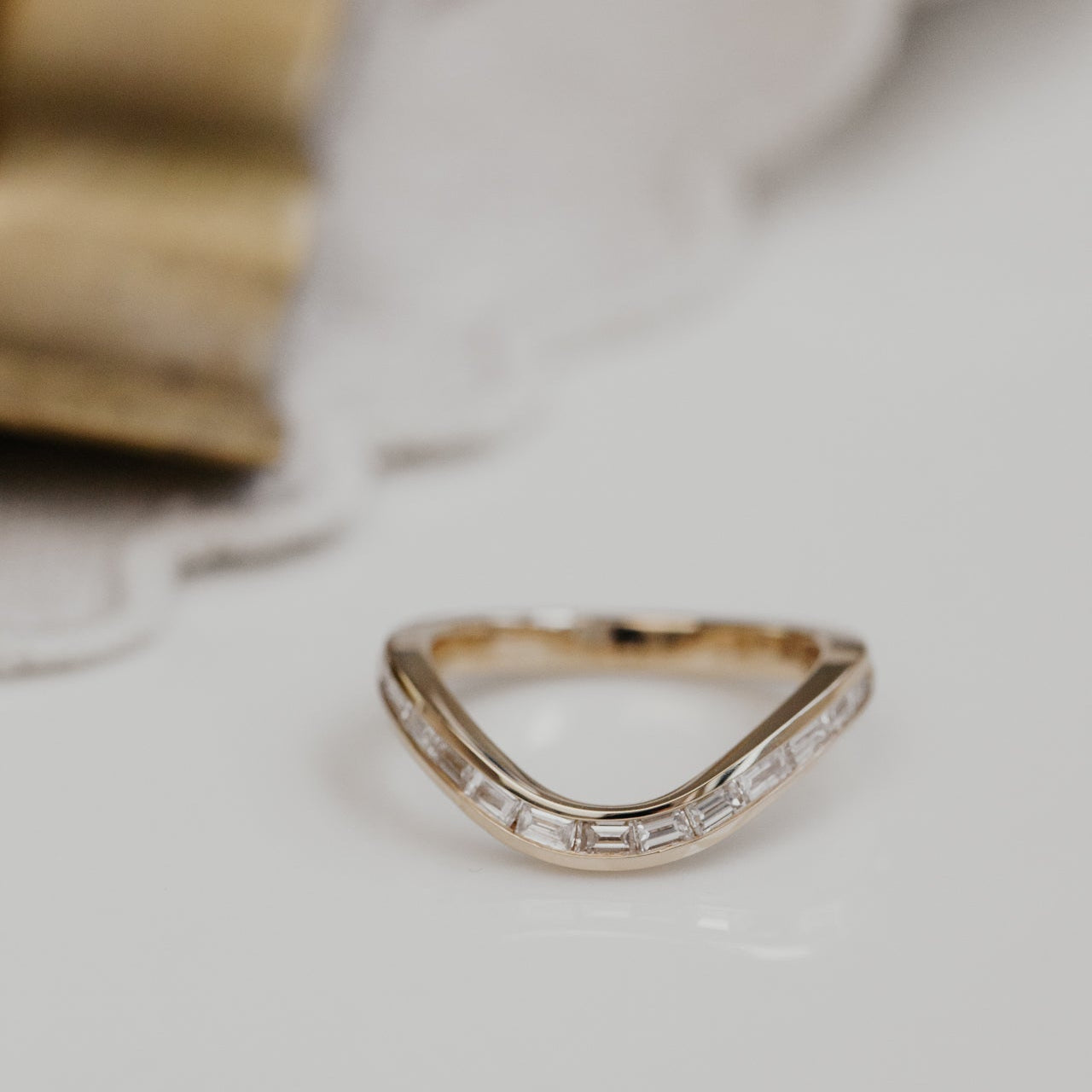Gold Equinox wedding band with diamond accents on a light background.