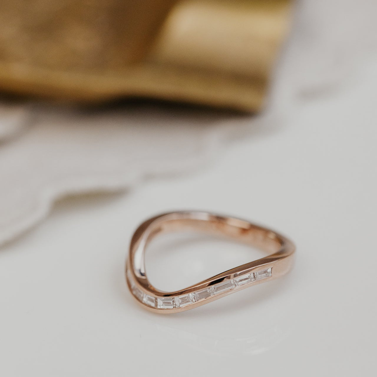 Rose wedding band with small diamonds on a light background