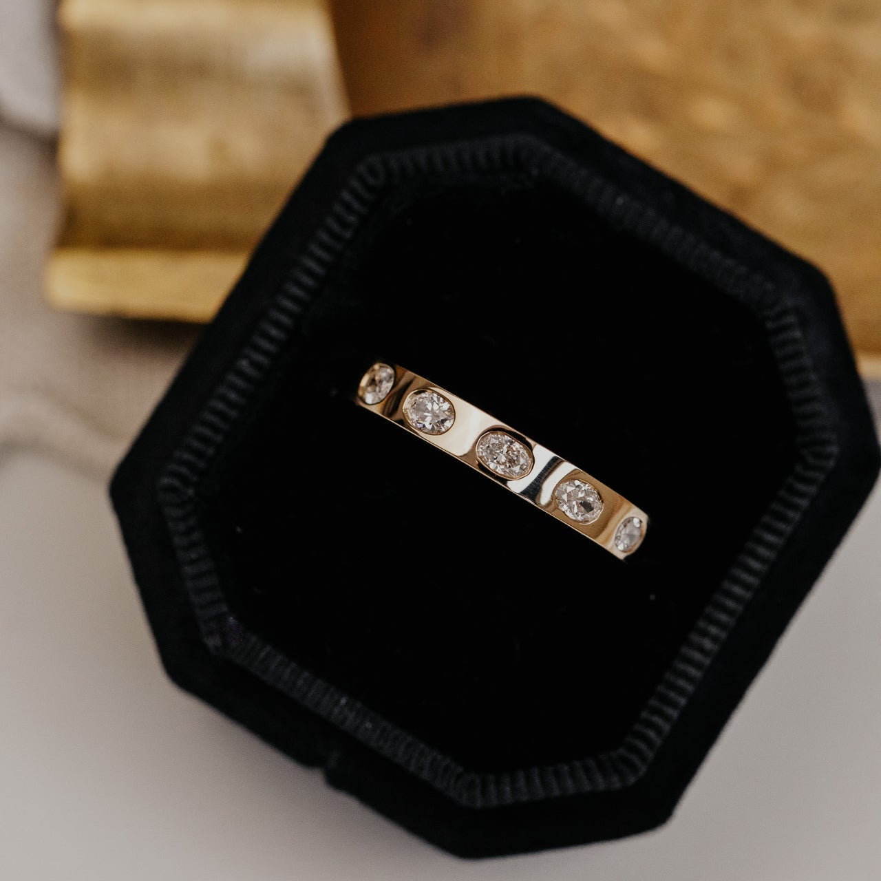 Gold wedding band with oval diamonds on a black hexagonal cushion