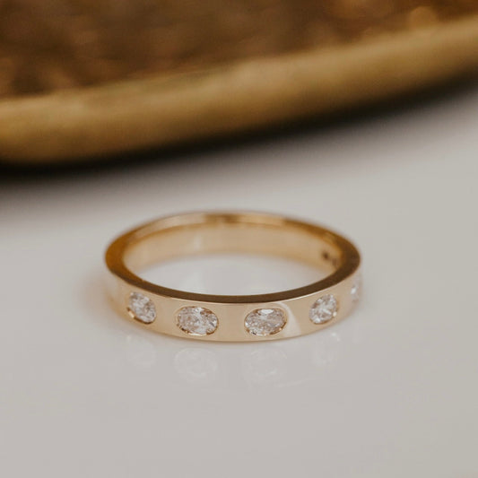 Gold wedding band with natural oval diamonds on a neutral background