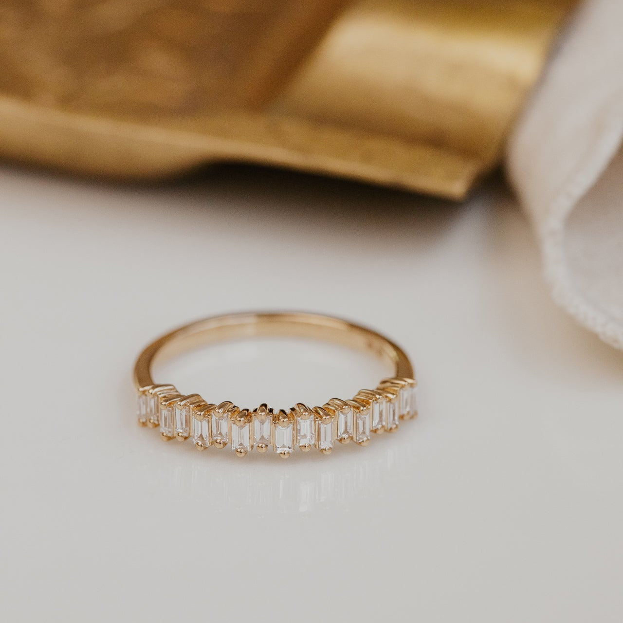 Gold wedding band with baguette diamonds on a light background