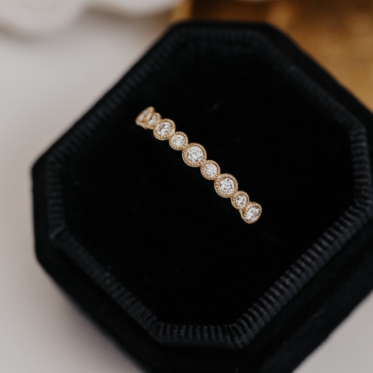 Gold wedding band with diamonds on a black velvet cushion
