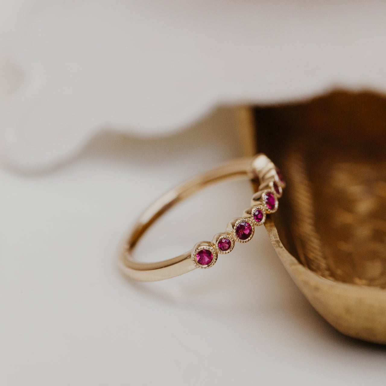 Gold wedding bad with red ruby gemstones on a textured surface