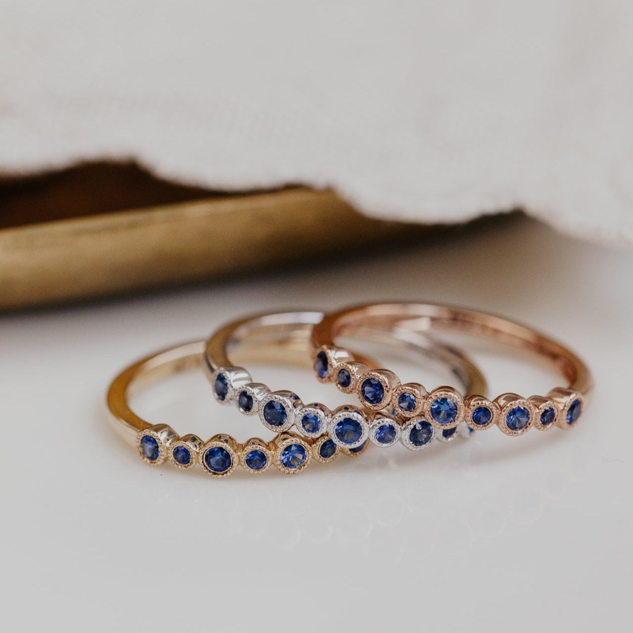 Three gold wedding band with blue sapphire gemstones on a light background