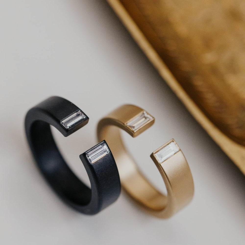 Black zirconium and gold bands on a neutral background