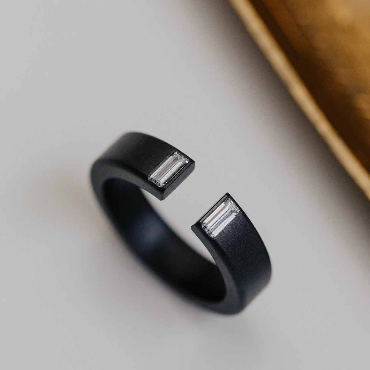 Black zirconium band with diamond accents on a light gray background