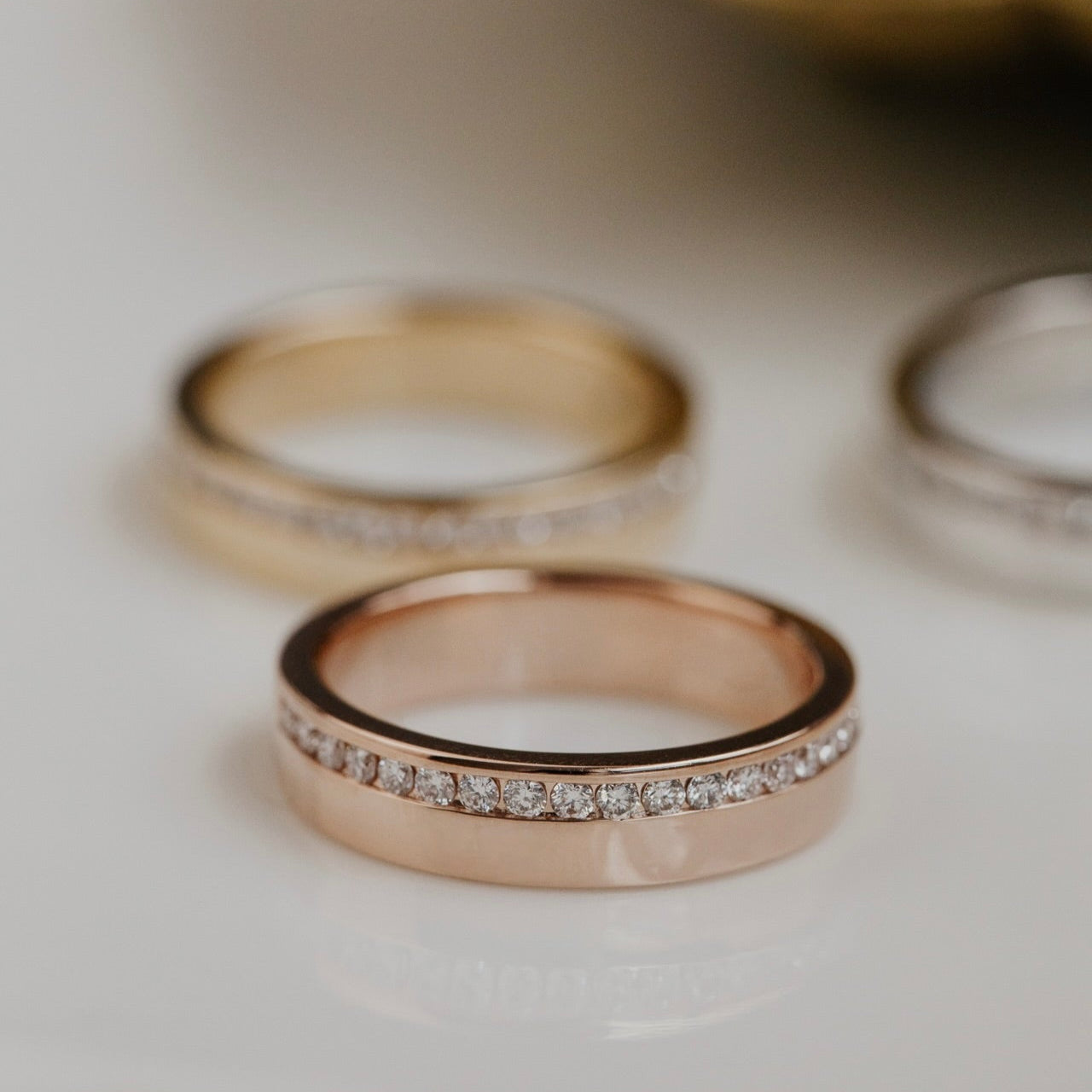 Two gold wedding bands with diamond accents on a light background