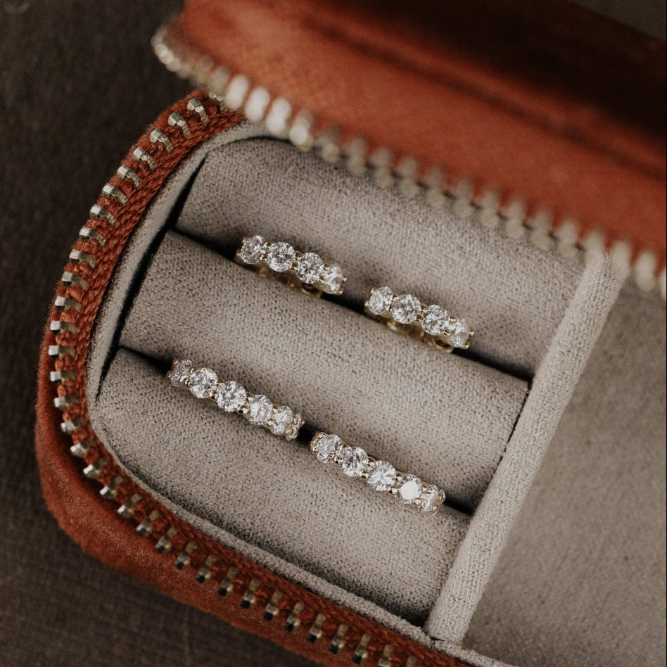 Set of diamond earrings in a brown jewelry box.