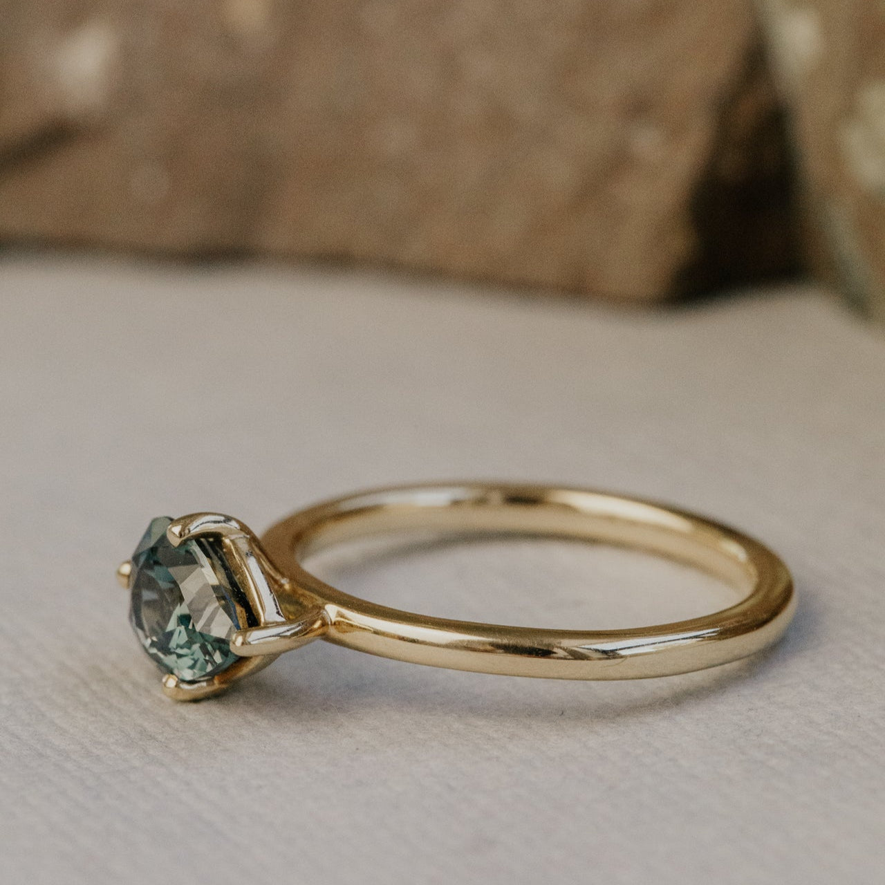 Gold ring with a green sapphire gemstone on a neutral background