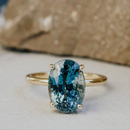 Gold ring with a blue gemstone on a textured surface