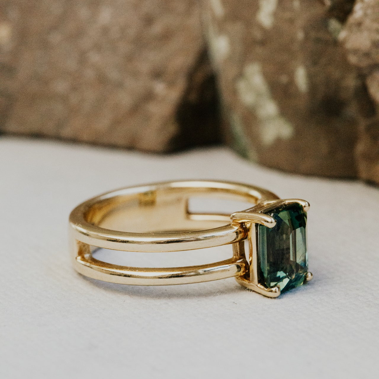 Gold ring with a green sapphire gemstone on a neutral background