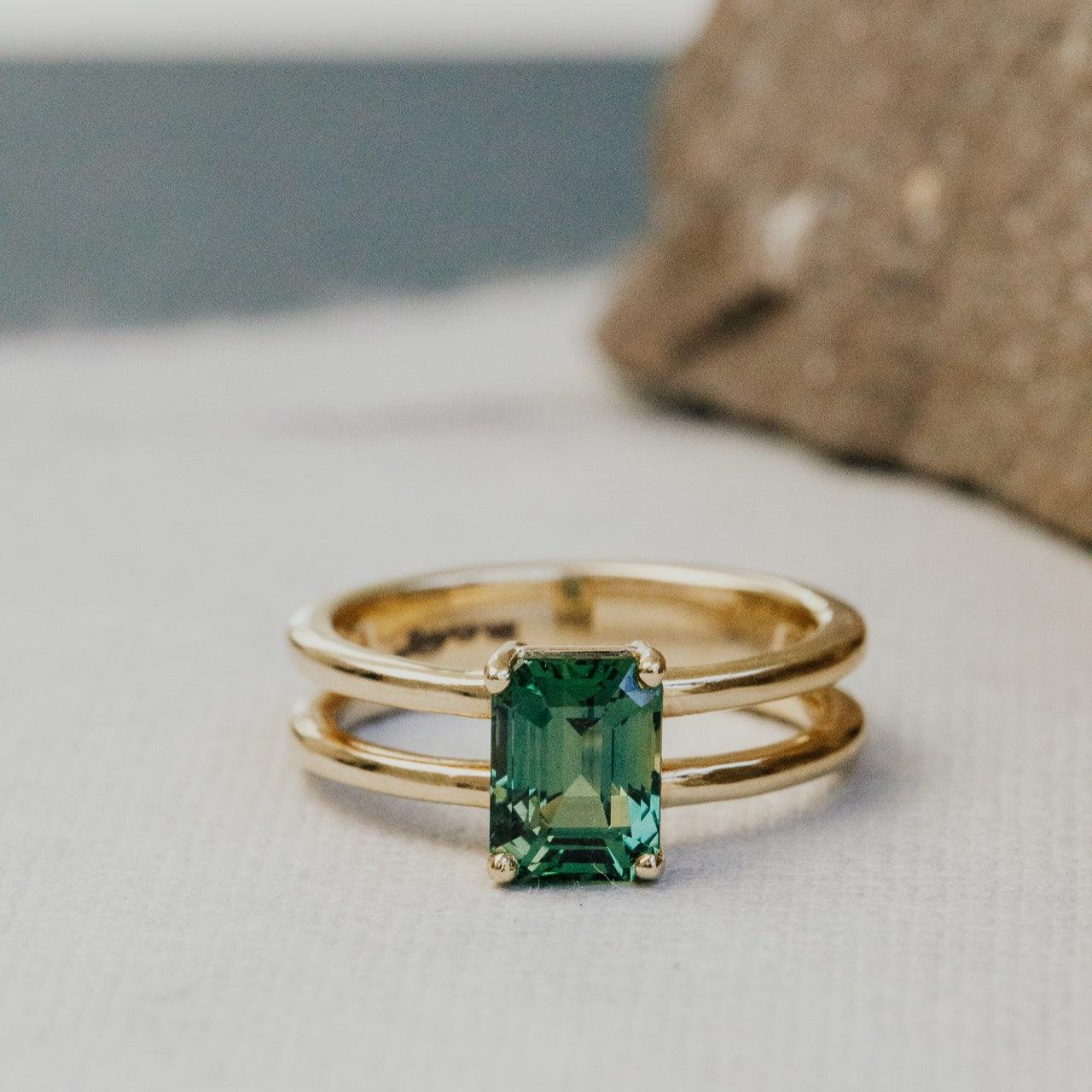 Gold ring with a green sapphire gemstone on a light surface