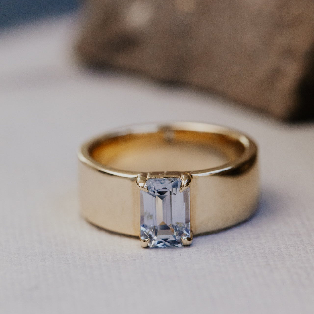 Gold ring with a blue sapphire gemstone on a neutral background