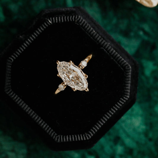 Marquise lab grown diamond ring in a black hexagonal box on a green textured background