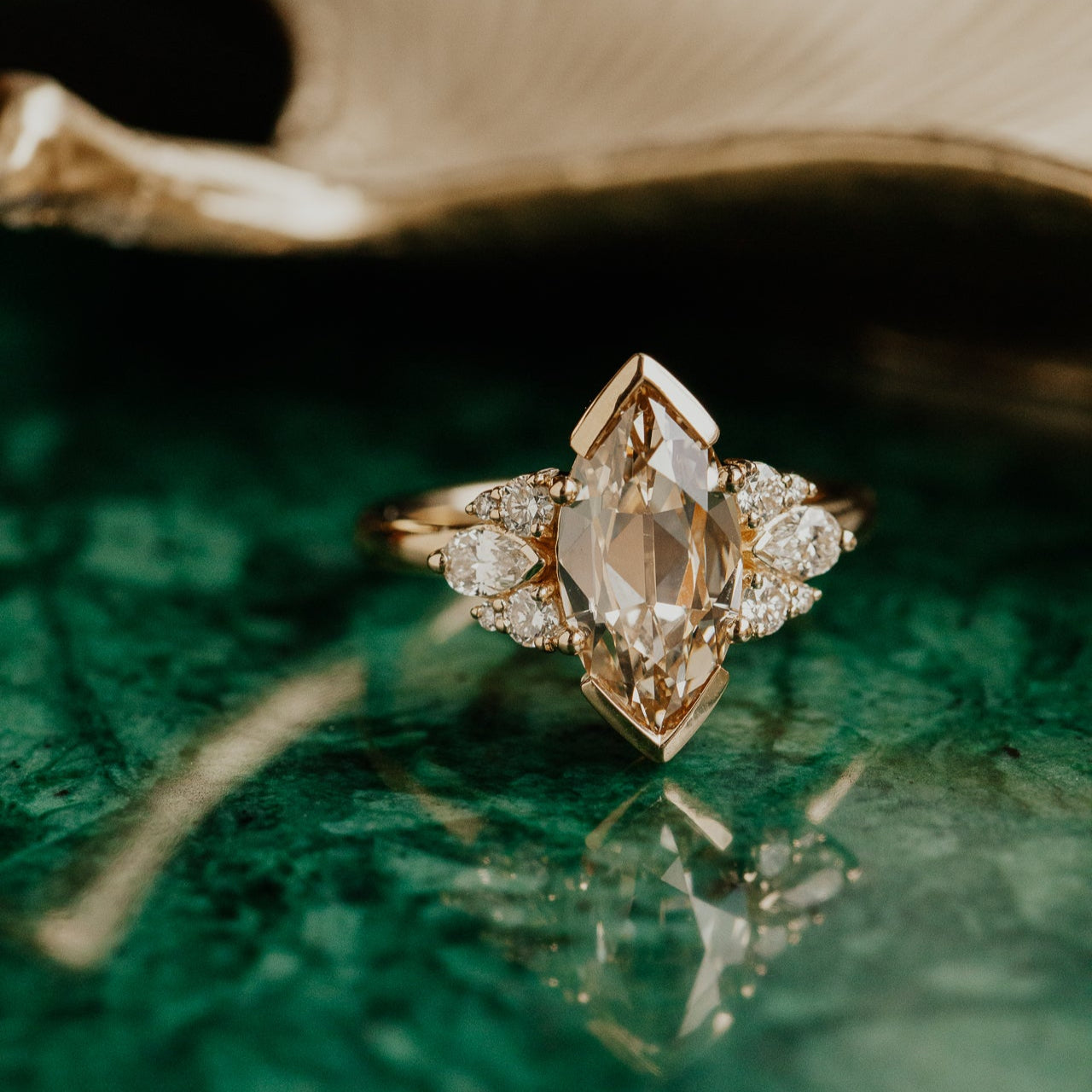Gold ring with a marquise old mine cut light yellow  diamond on a green surface