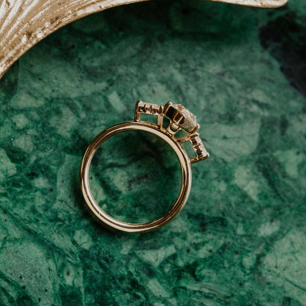 Gold ring with a key design on a green marble surface