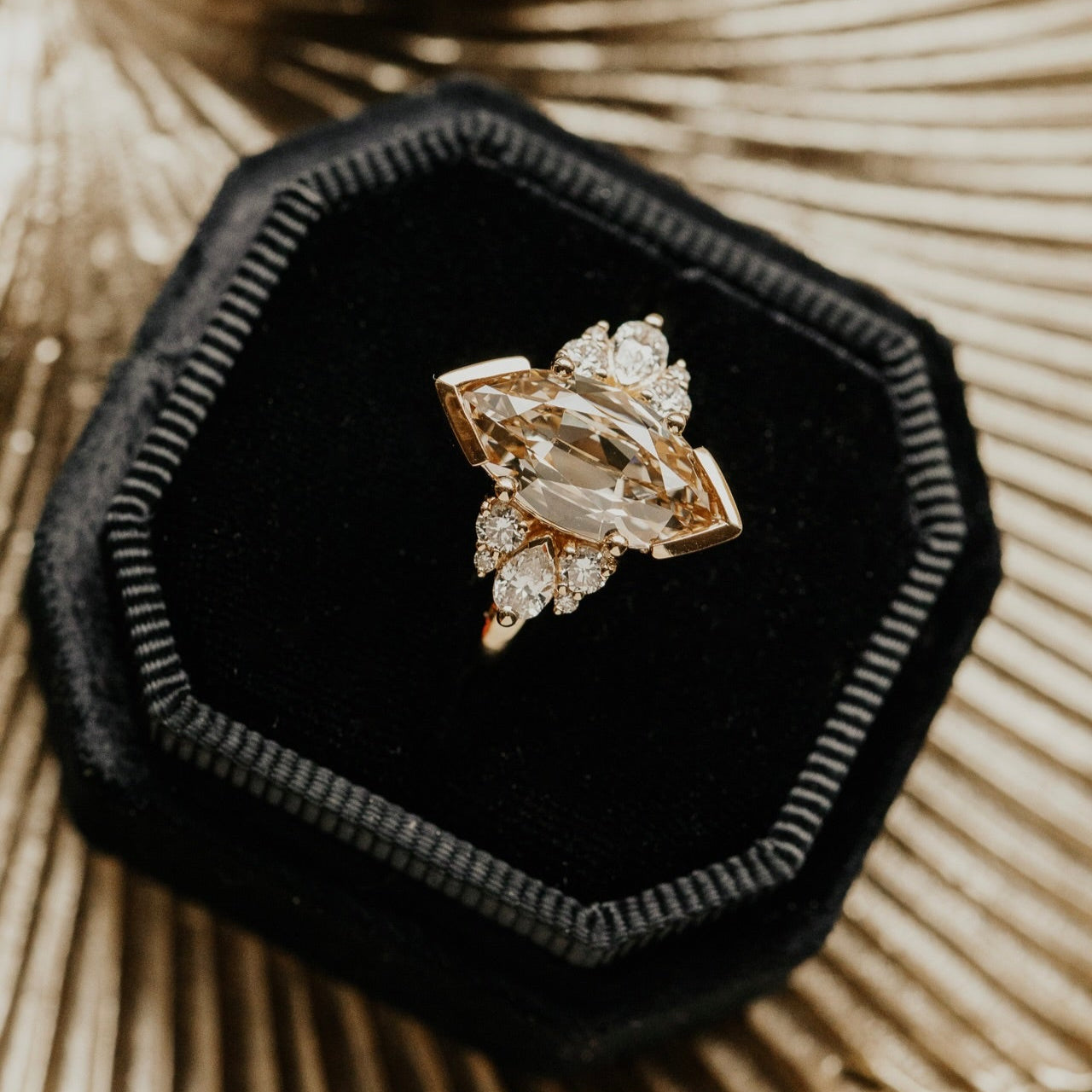 Marquise old mine cut light yellow diamond ring on a black velvet cushion with a natural background