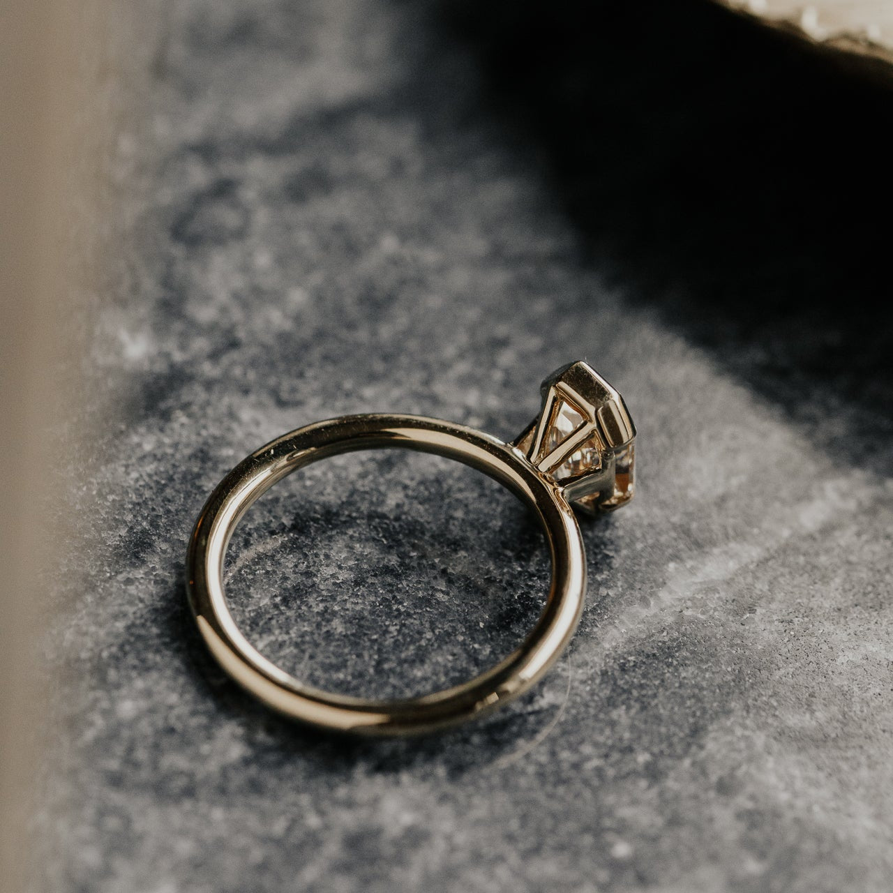 Gold ring with a diamond on a textured stone surface