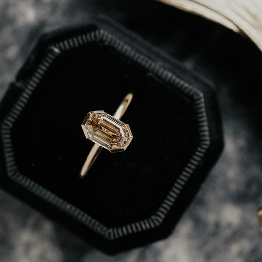 Diamond ring in a black velvet box with a shell in the background