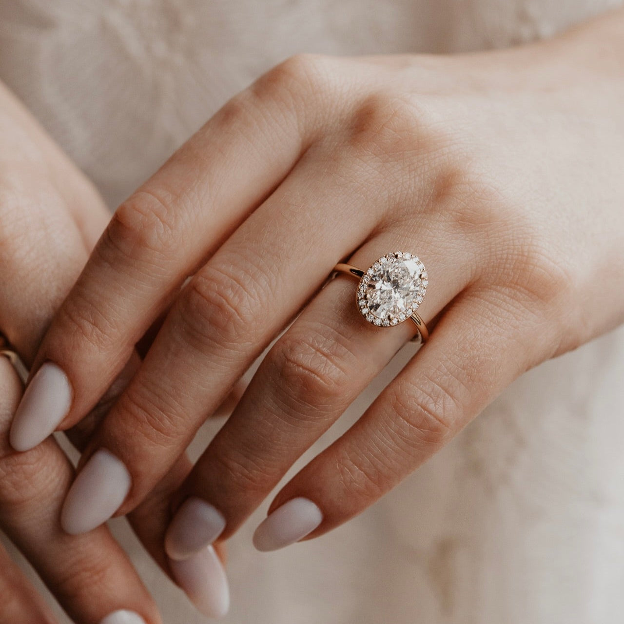 The Audrey oval diamond engagement ring with a diamond halo in 14k yellow gold on a models hand
