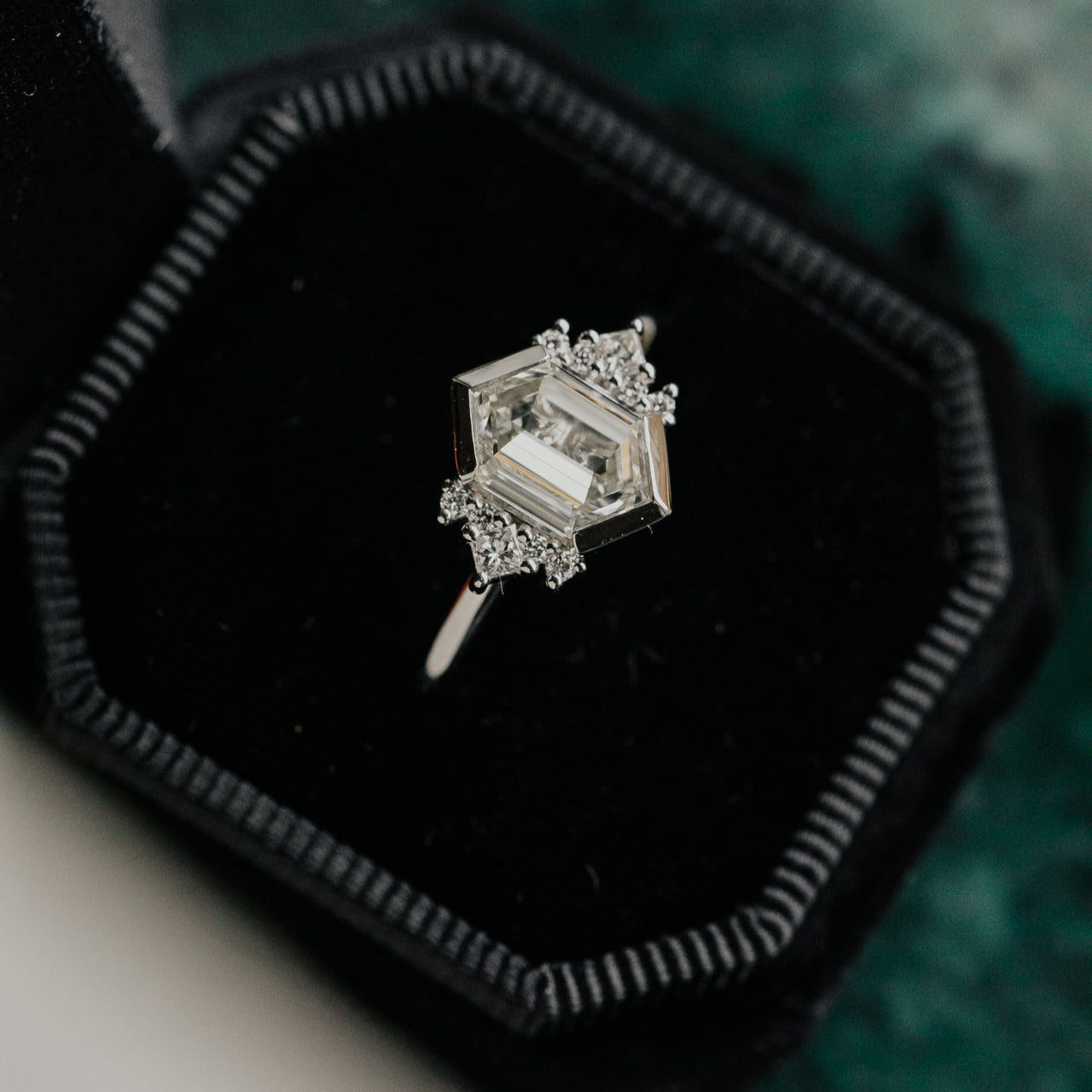 Diamond ring in a black velvet box on a textured green surface