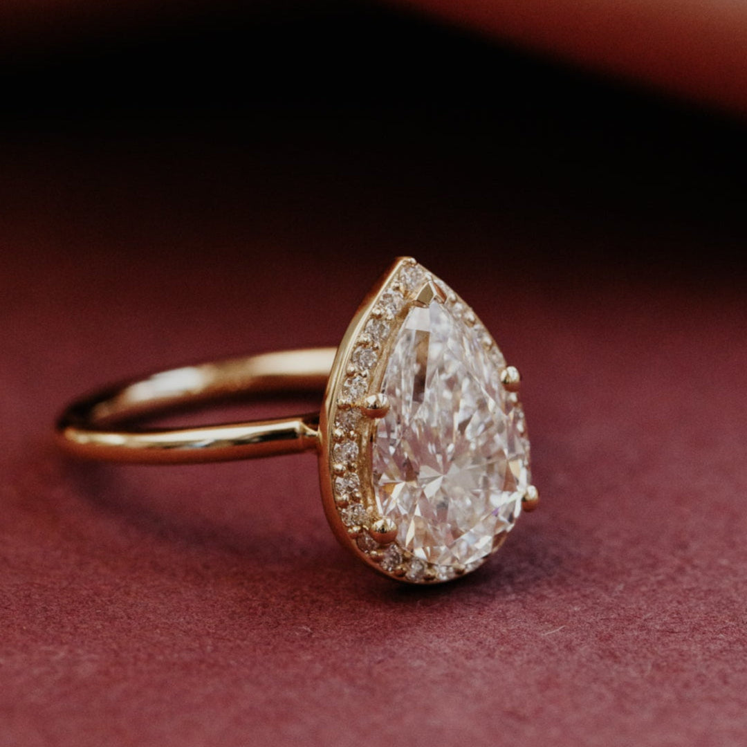 Gold ring with a large pear-shaped diamond on a dark background