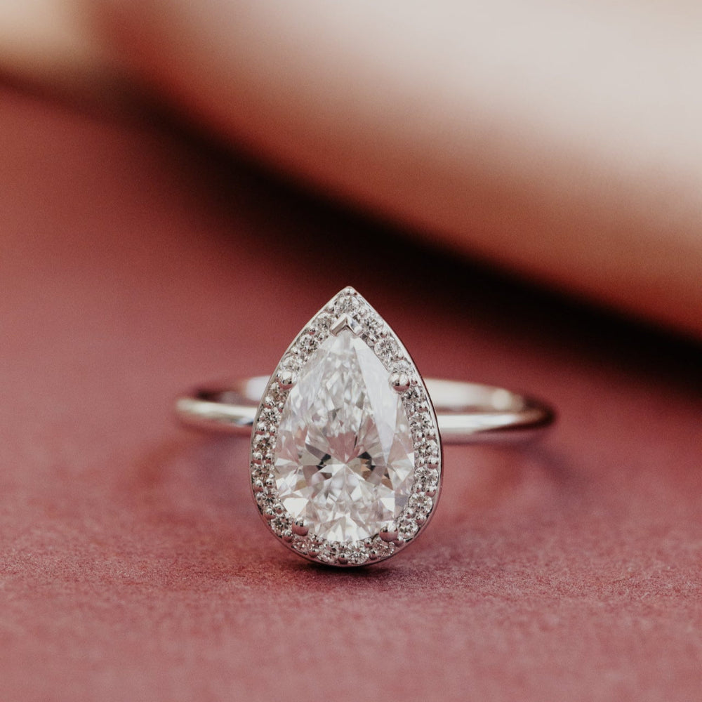 Pear-shaped diamond ring on a pink surface