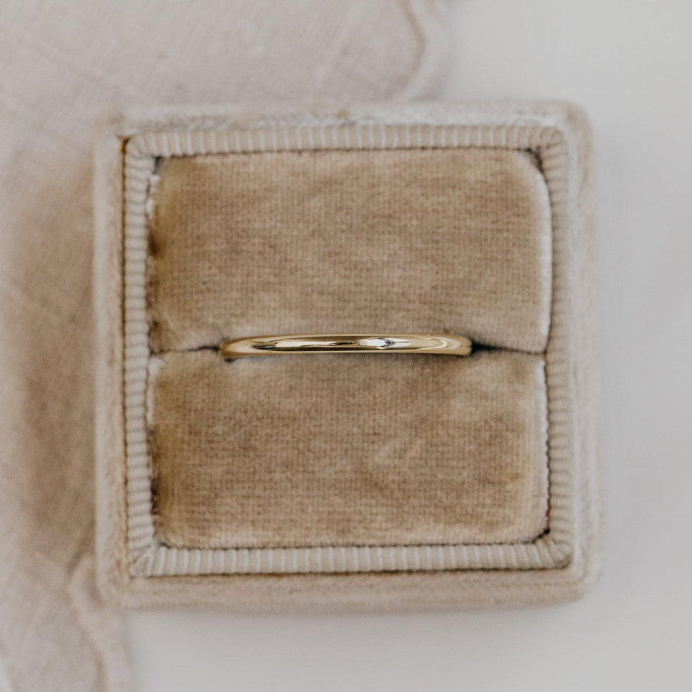 Gold ring in a beige jewelry box on a light background