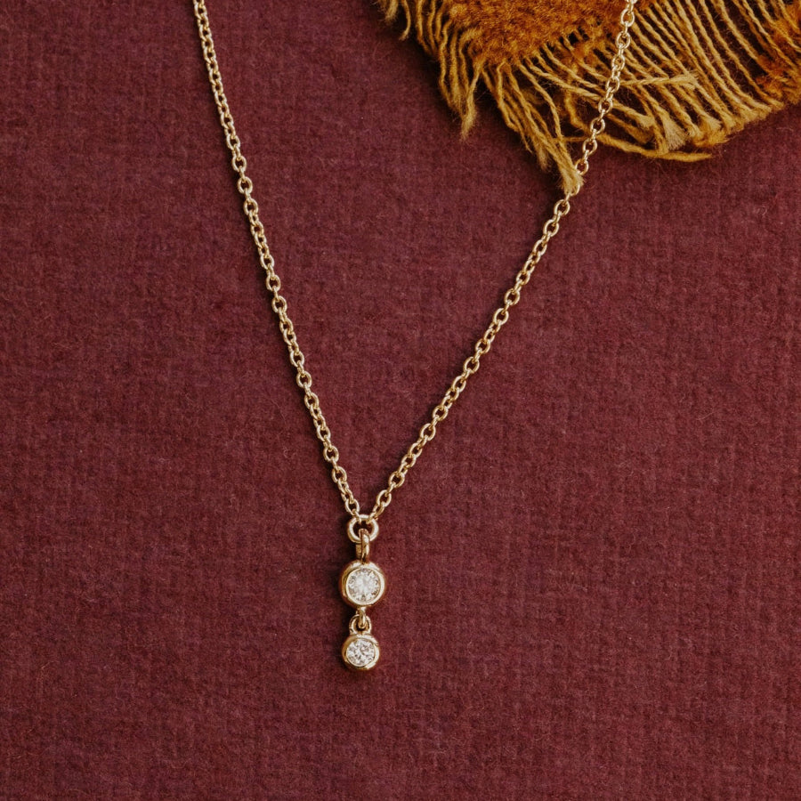 Gold necklace with a diamond pendant on a textured red surface