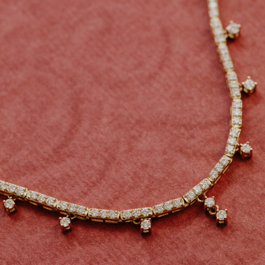 Gold necklace with diamond accents on a red background
