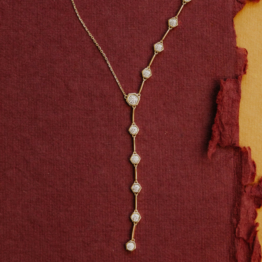 Delicate diamond lariat necklace on a textured red fabric background