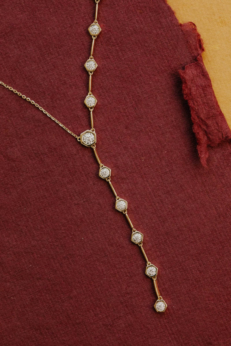 Delicate gold necklace with diamond stones on a red fabric background