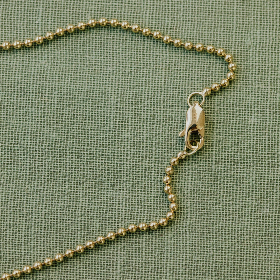Gold chain necklace on a textured green background