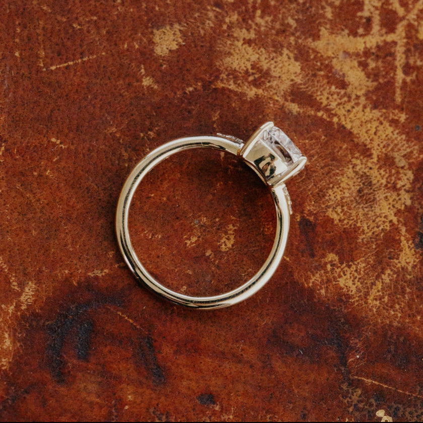 Gold ring with a cushion cut diamond on a textured brown surface