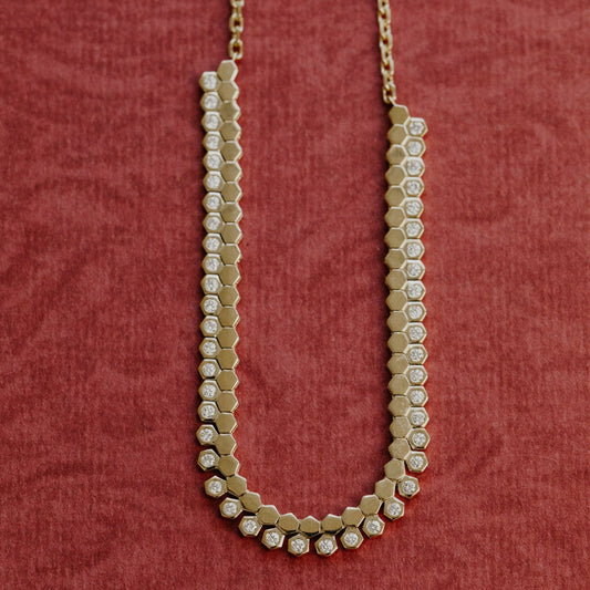 Gold necklace with hexagonal beads on a red textured background