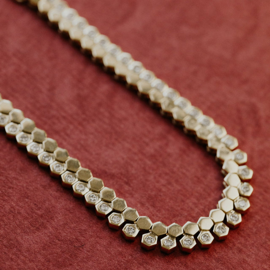 Gold necklace with hexagonal diamonds on a red background