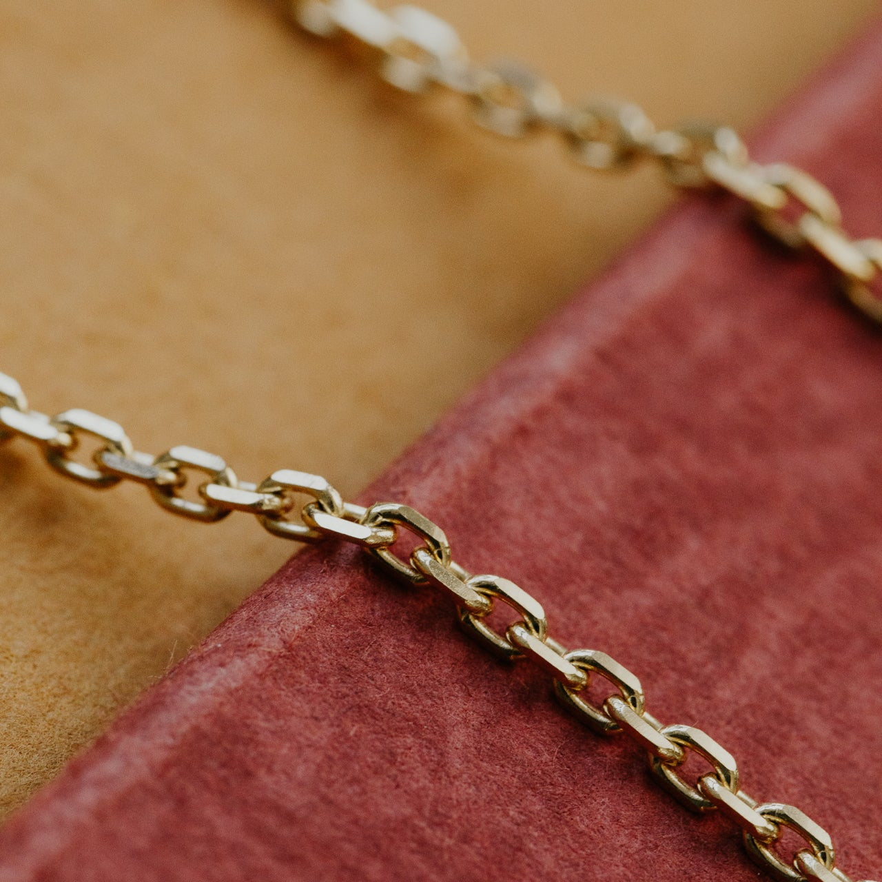 Gold chain on a textured red and beige surface