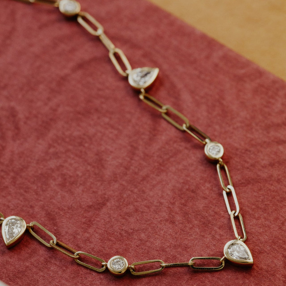 Gold chain necklace with diamonds on a red fabric background