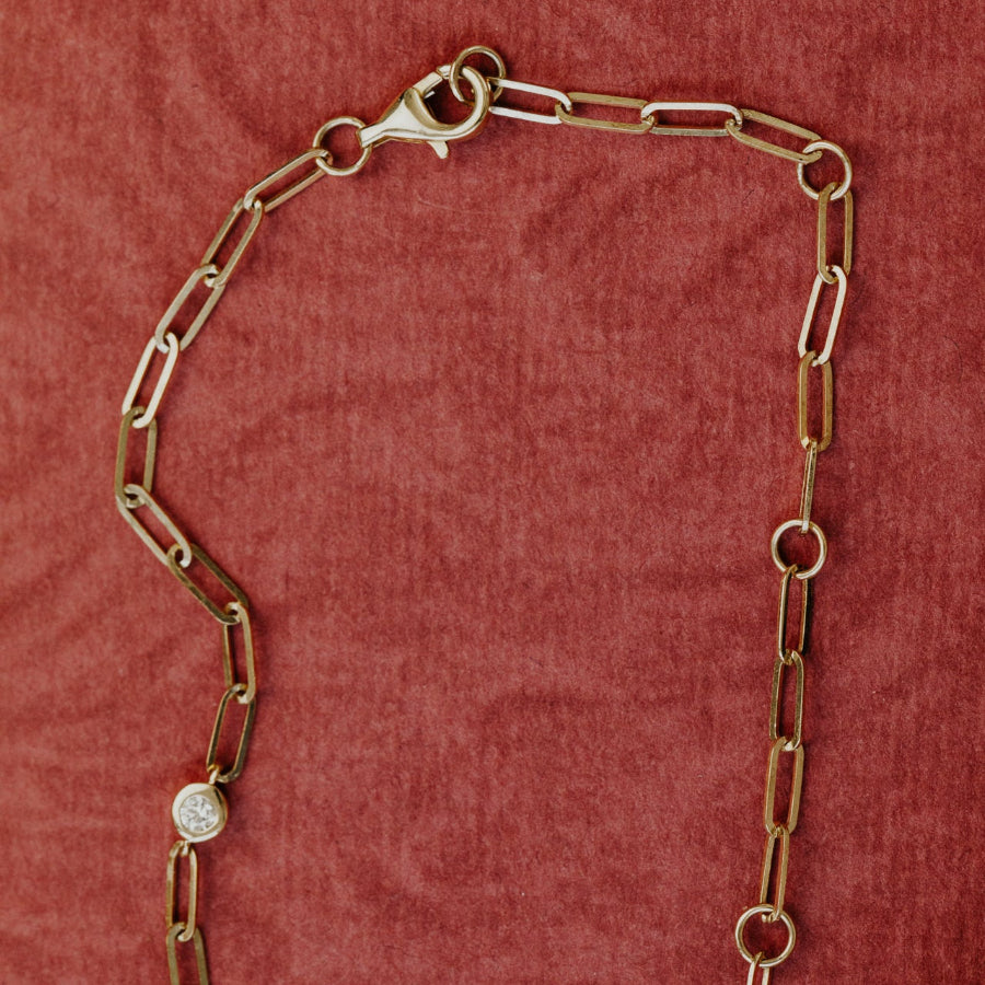 Gold chain necklace with a clasp on a red textured background
