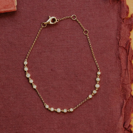 Gold bracelet with diamond beads on a textured red fabric background