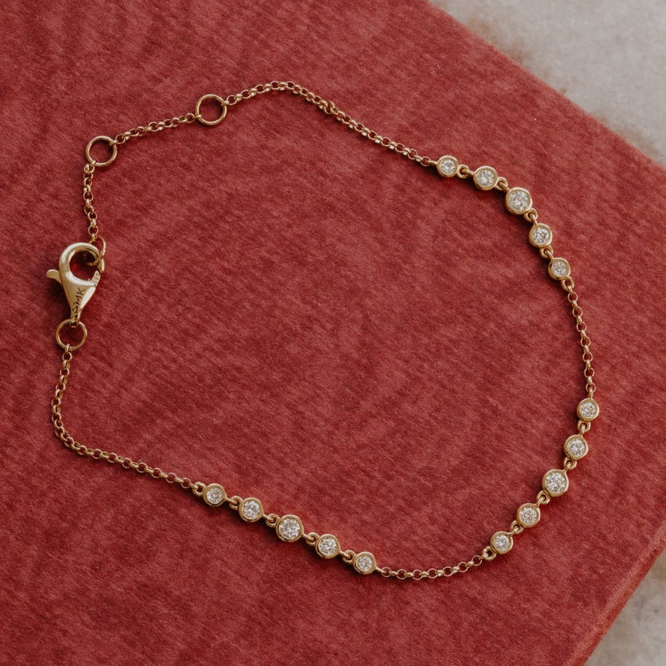 Gold bracelet with diamond beads on a red surface