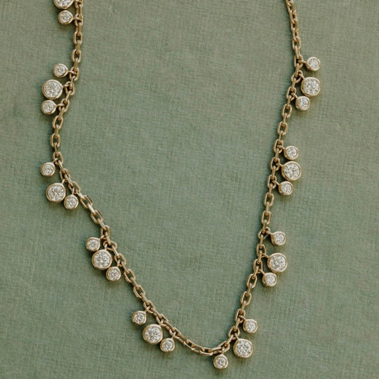 Delicate necklace with small diamonds on a green fabric background