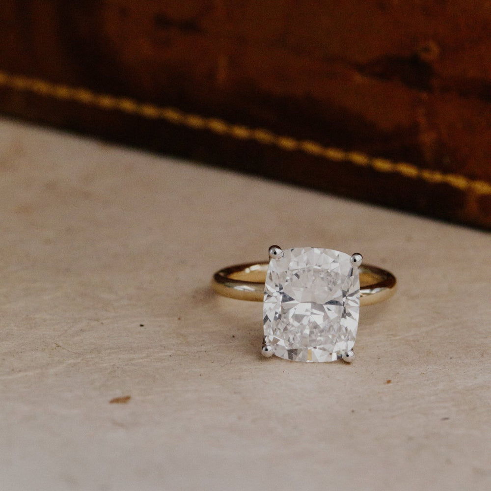 Gold ring with a large elongated cushion diamond on a textured surface