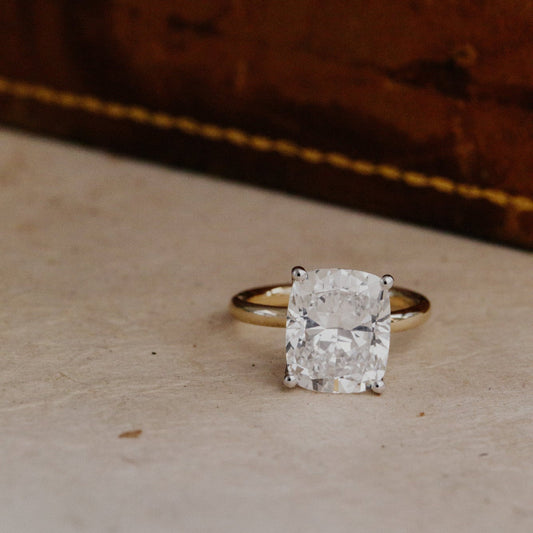 Gold ring with a large elongated cushion diamond on a textured surface
