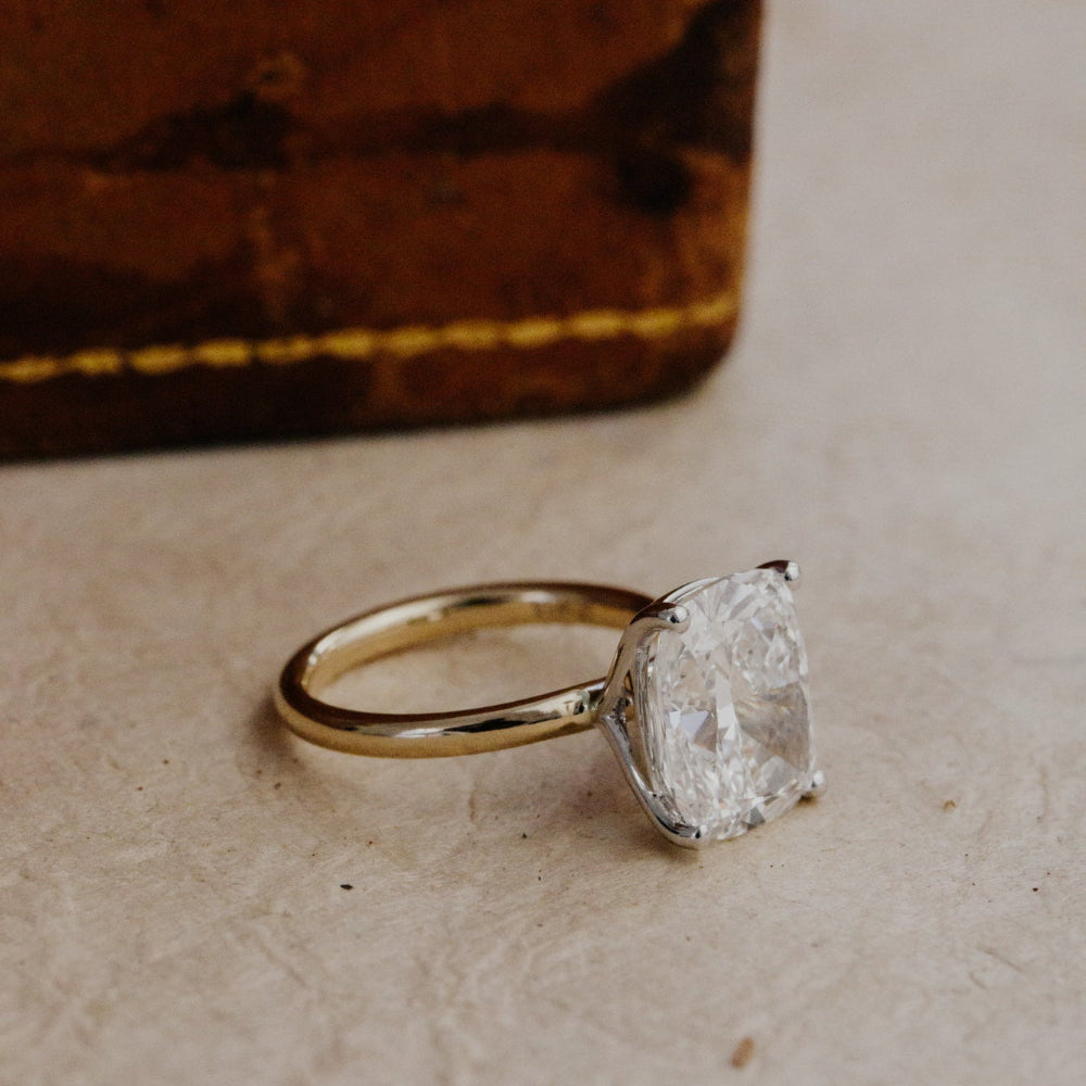 Gold ring with a large, elongated cushion diamond on a textured surface