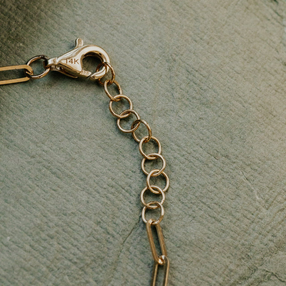 Gold chain with clasp on a textured green surface