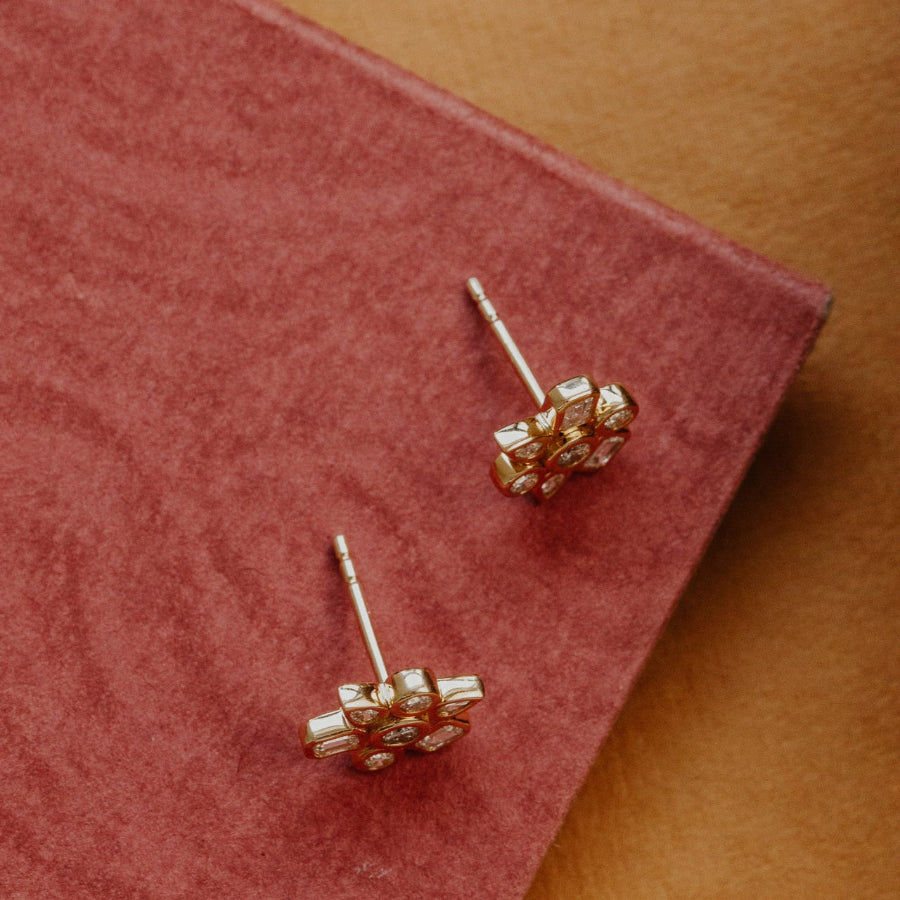 Gold earrings on a red velvet surface with a brown background