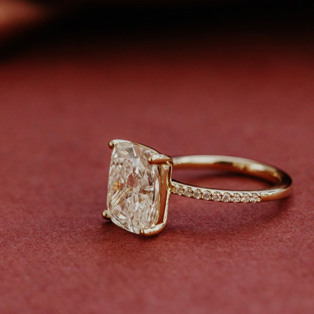 Yellow gold ring with a large Elongated cushion diamond on a brown background