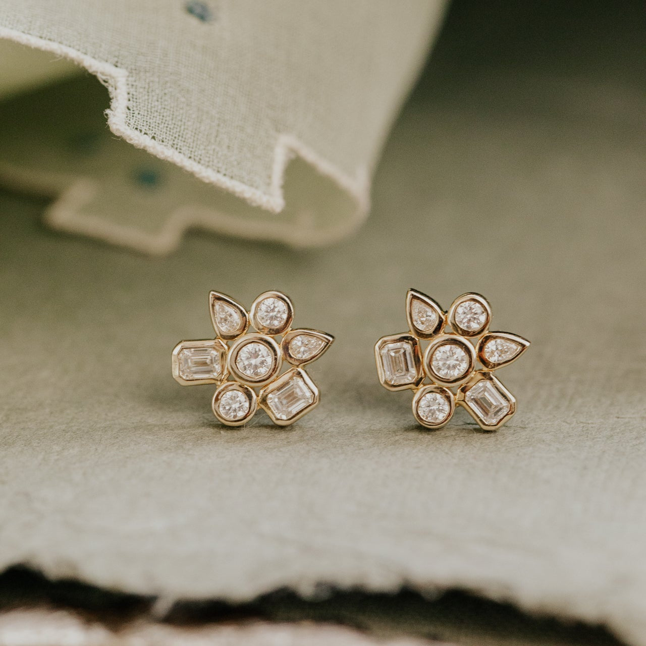 Pair of diamond stud earrings on a textured fabric background