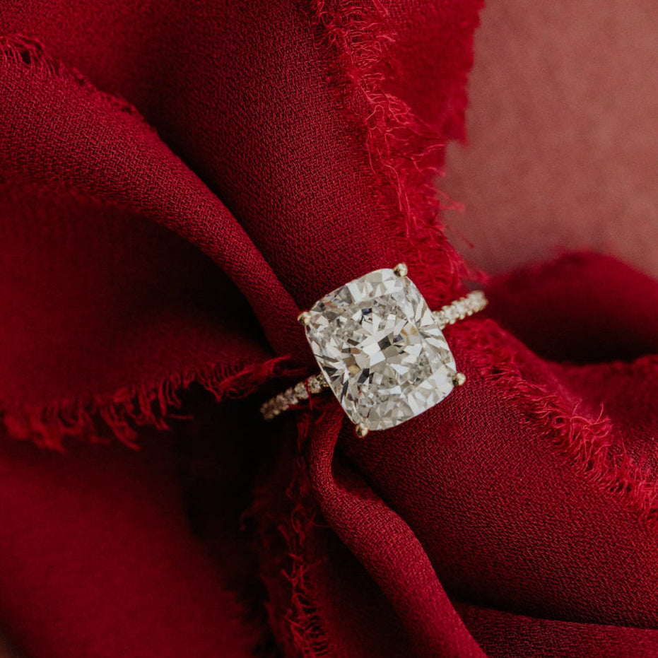 Elongated cushion diamond ring on a red fabric background
